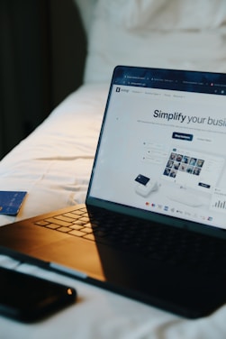Laptop, phone, and card on a bed.
