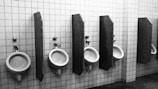 Urinals in a bathroom, separated by wood.