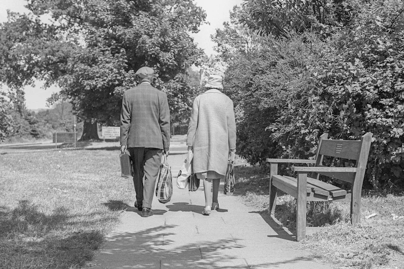 An older couple walking through a park