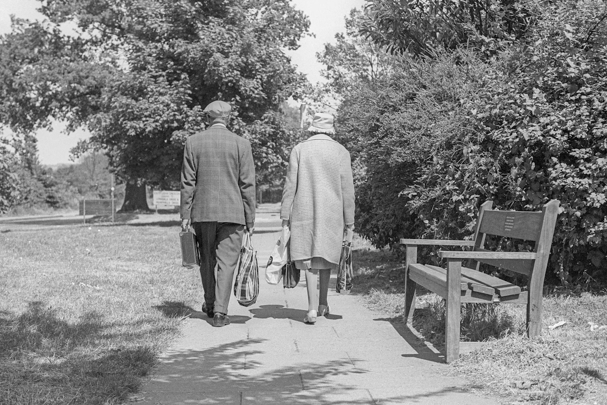 An elderly couple walking together through a park - long-standing clients