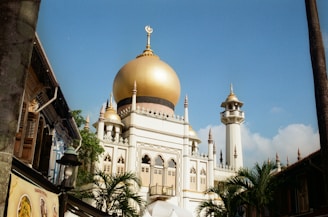 A golden domed mosque under a bright blue sky.