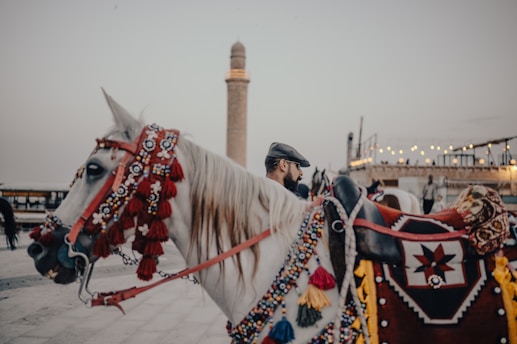 A decorated horse stands with a religious structure.