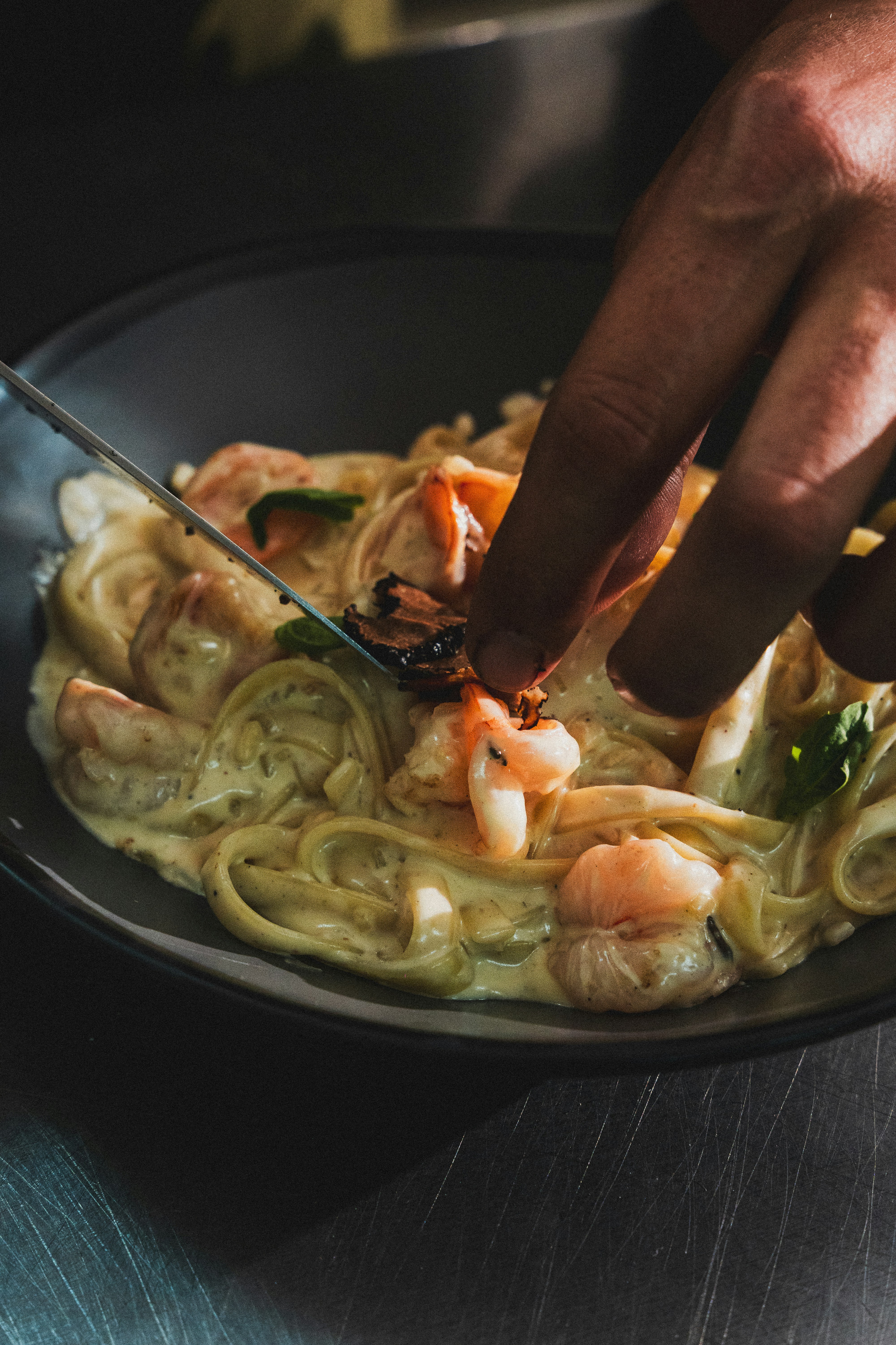 El chef adorna un cremoso plato de pasta de mariscos.