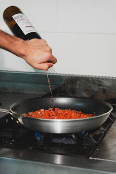 Red wine is being poured into a pan.