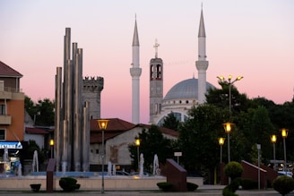 A mosque and fountain under a pink sunset.