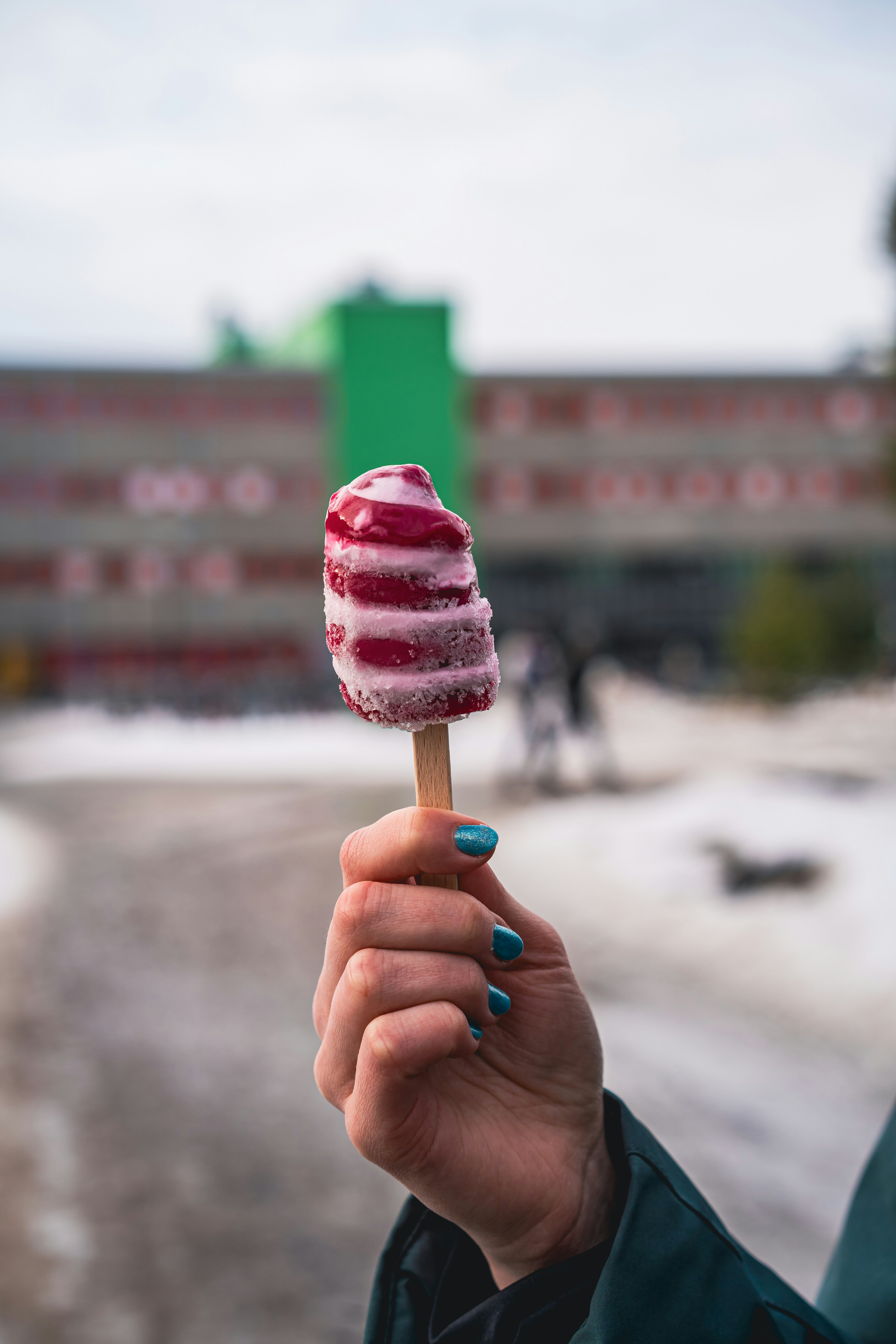 Hand holding a colorful, swirled popsicle.
