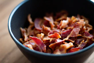 Crispy cambodia bacon pieces fill a black bowl.