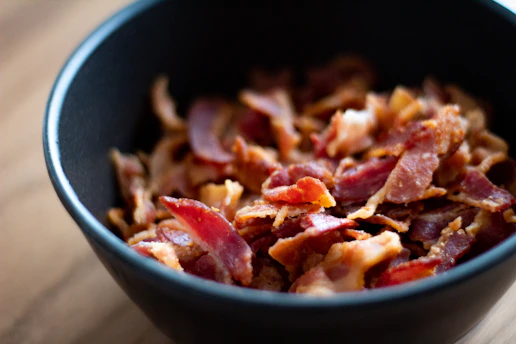 Crispy cambodia bacon pieces fill a black bowl.