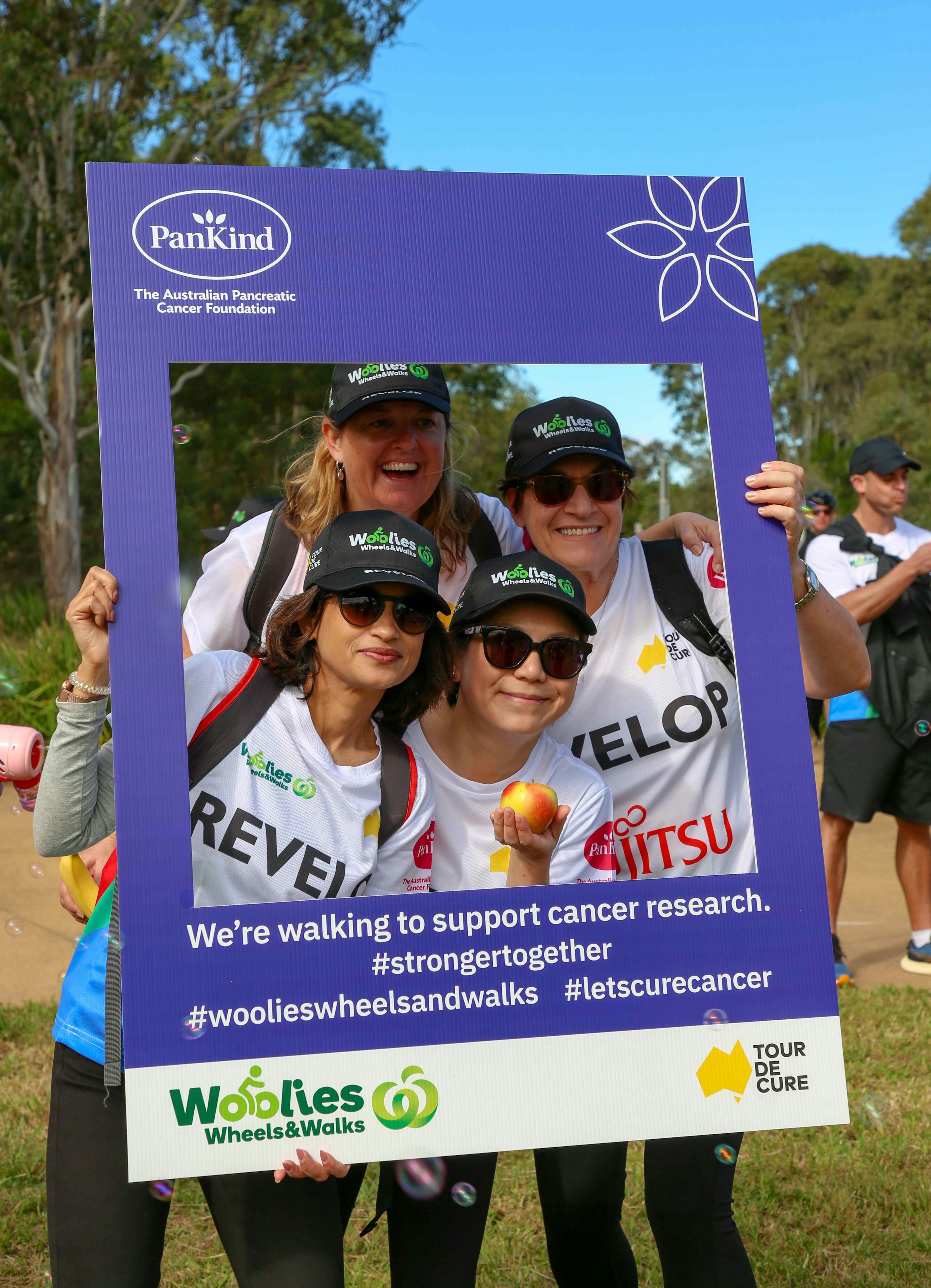 Four people are posing in a frame to support cancer research.
