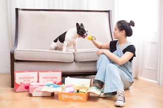 A woman feeds a dog on a couch.