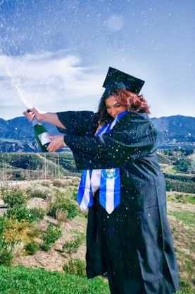 Graduating student joyfully pops champagne.