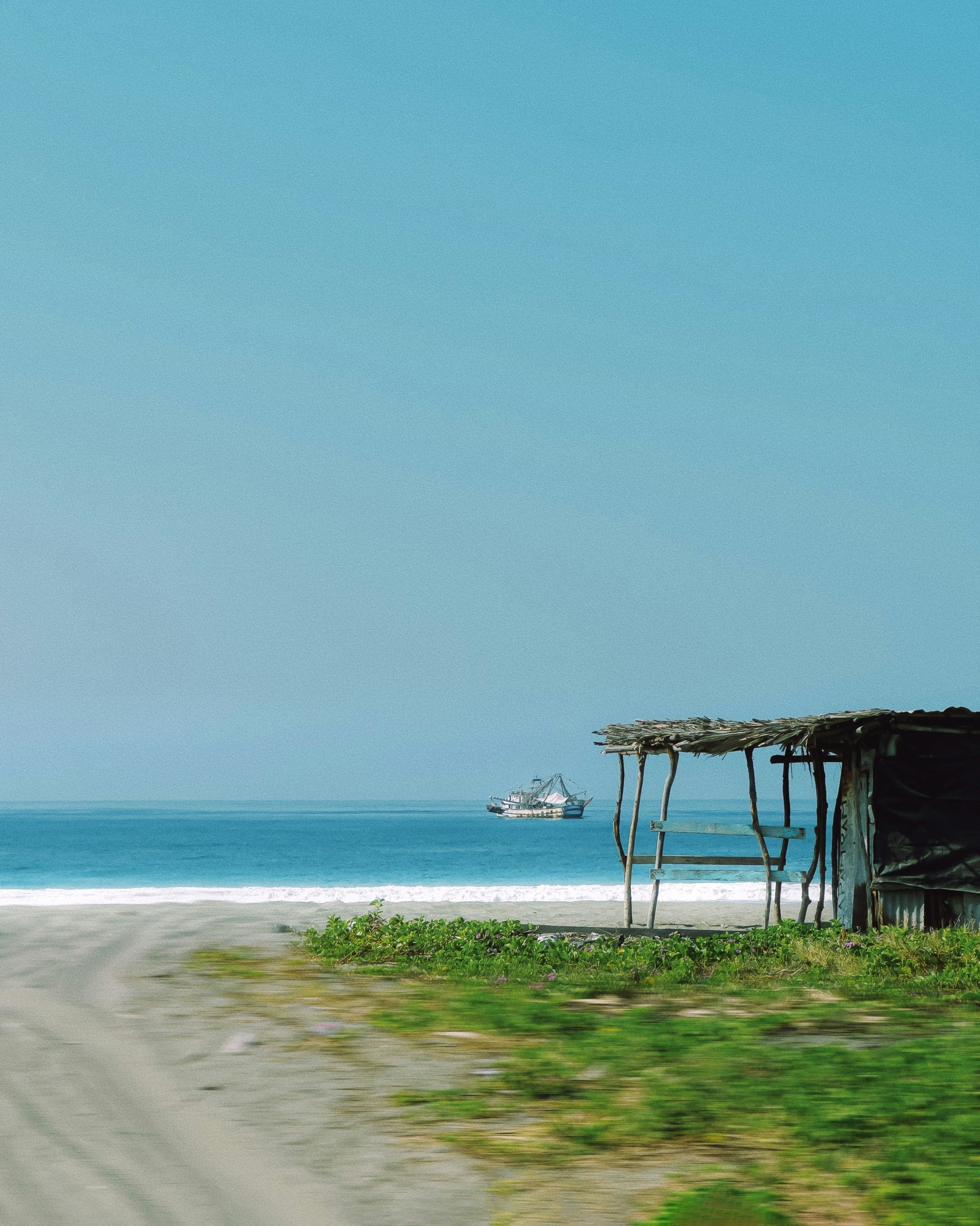 A beach scene with a small boat on the water.