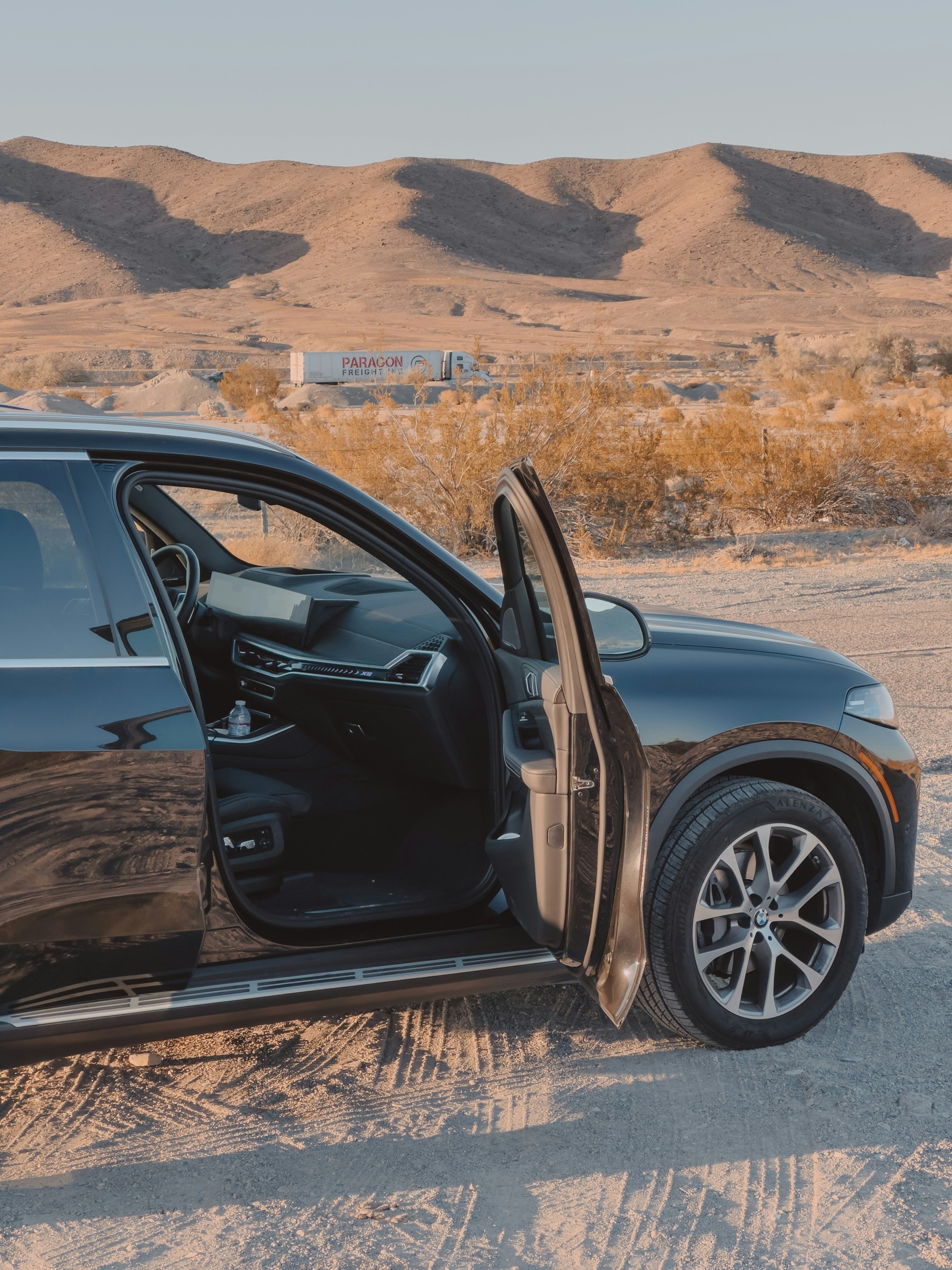 A black suv sits by a scenic desert landscape.