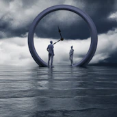 People stand inside a clock on the water.