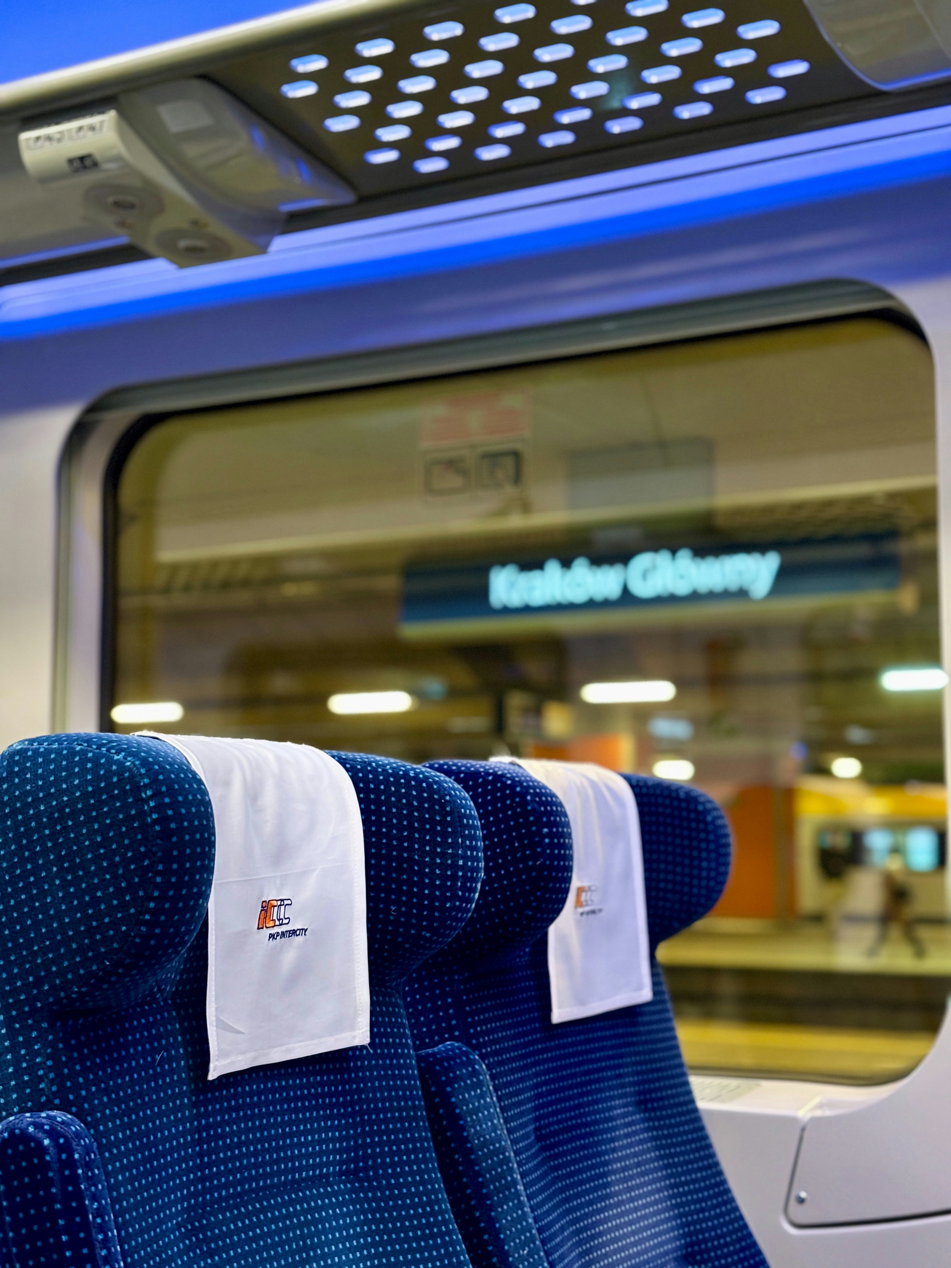 Inside a train with seats and a station sign.