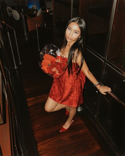 Young woman in red dress holds red roses.
