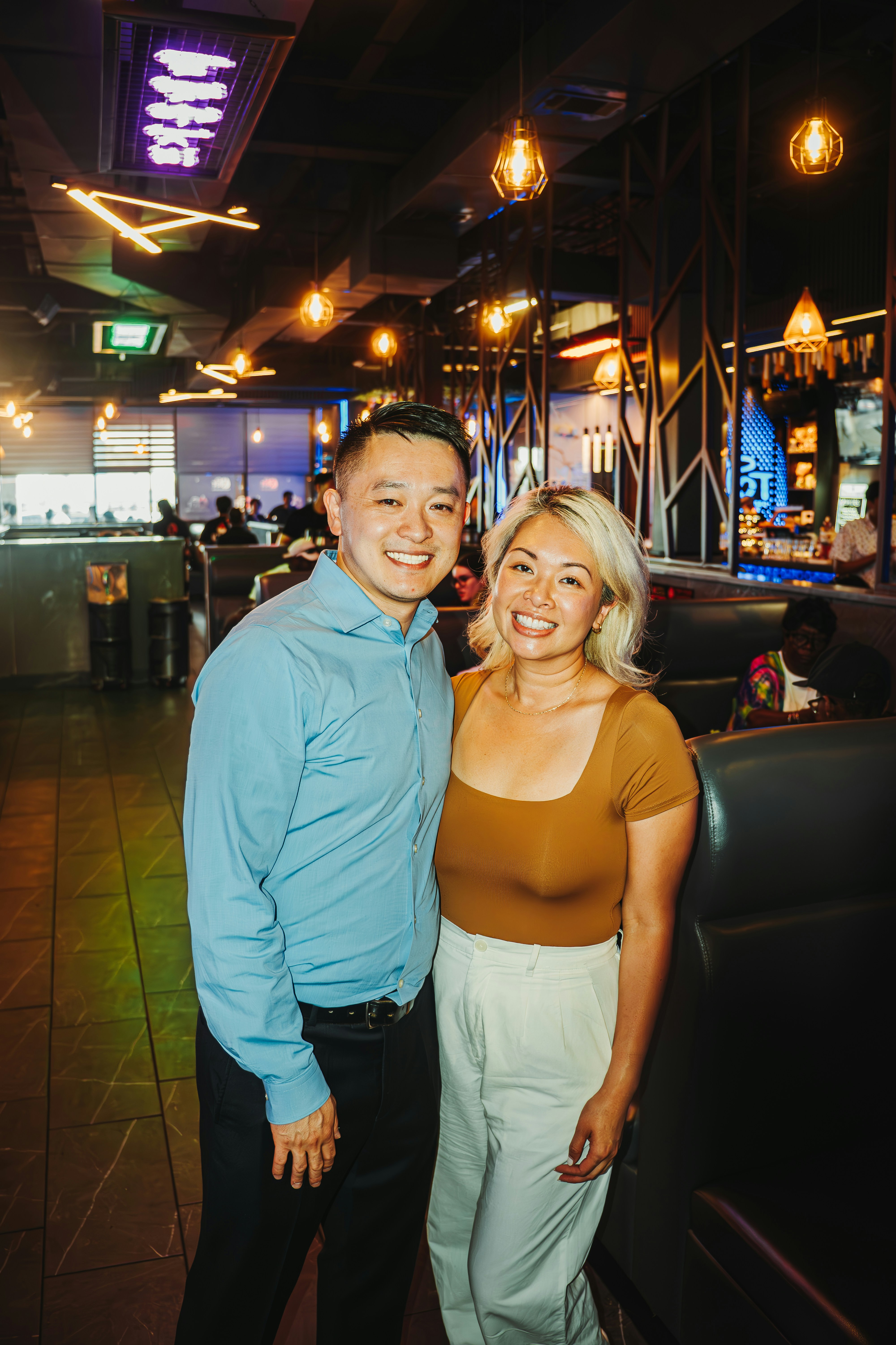 A smiling couple poses inside a restaurant.