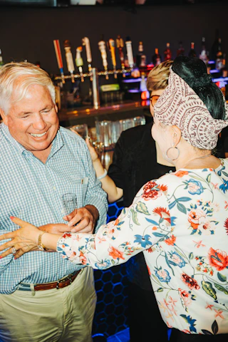 People are laughing and chatting at a bar.