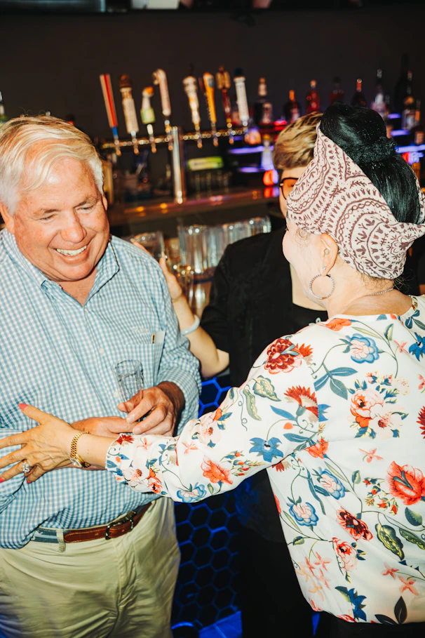 People are laughing and chatting at a bar.