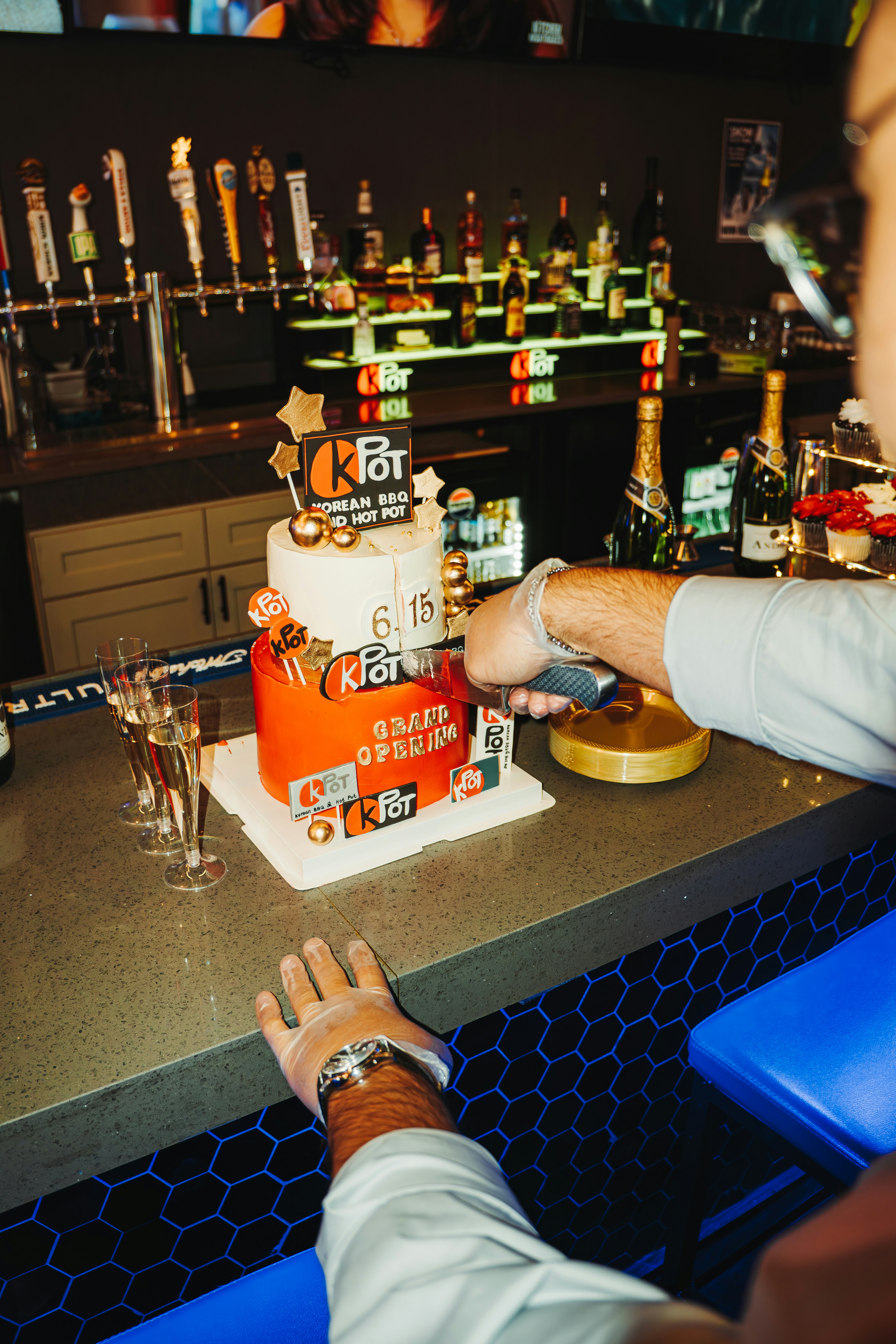 A person cuts a cake at a bar.