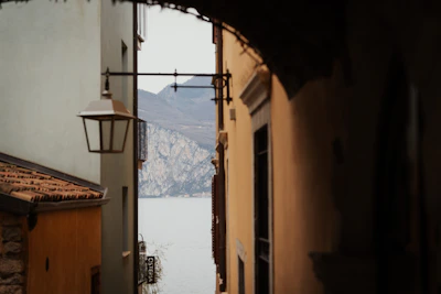 A narrow alleyway reveals a lake and mountains.
