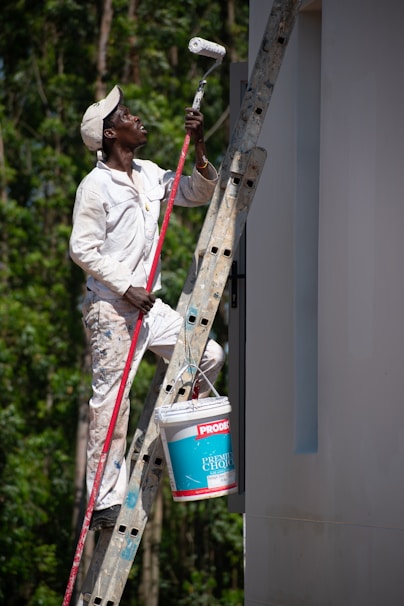 A painter diligently paints a wall on a ladder.