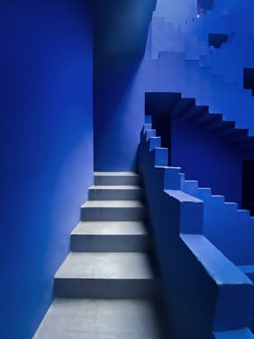 Blue stairs ascend within a monochromatic structure.
