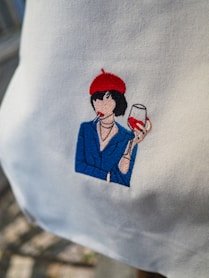 Embroidered image of a woman with wine and cigarette.