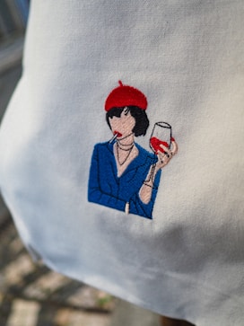 Embroidered image of a woman with wine and cigarette.