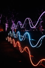 Neon lights illuminate wave-like shapes at night.