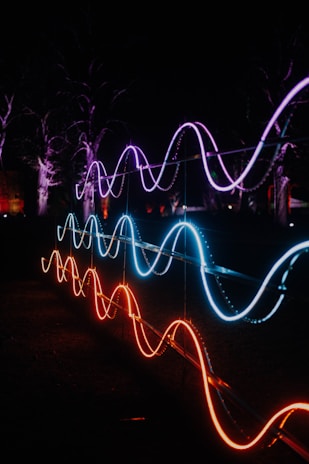 Neon lights illuminate wave-like shapes at night.