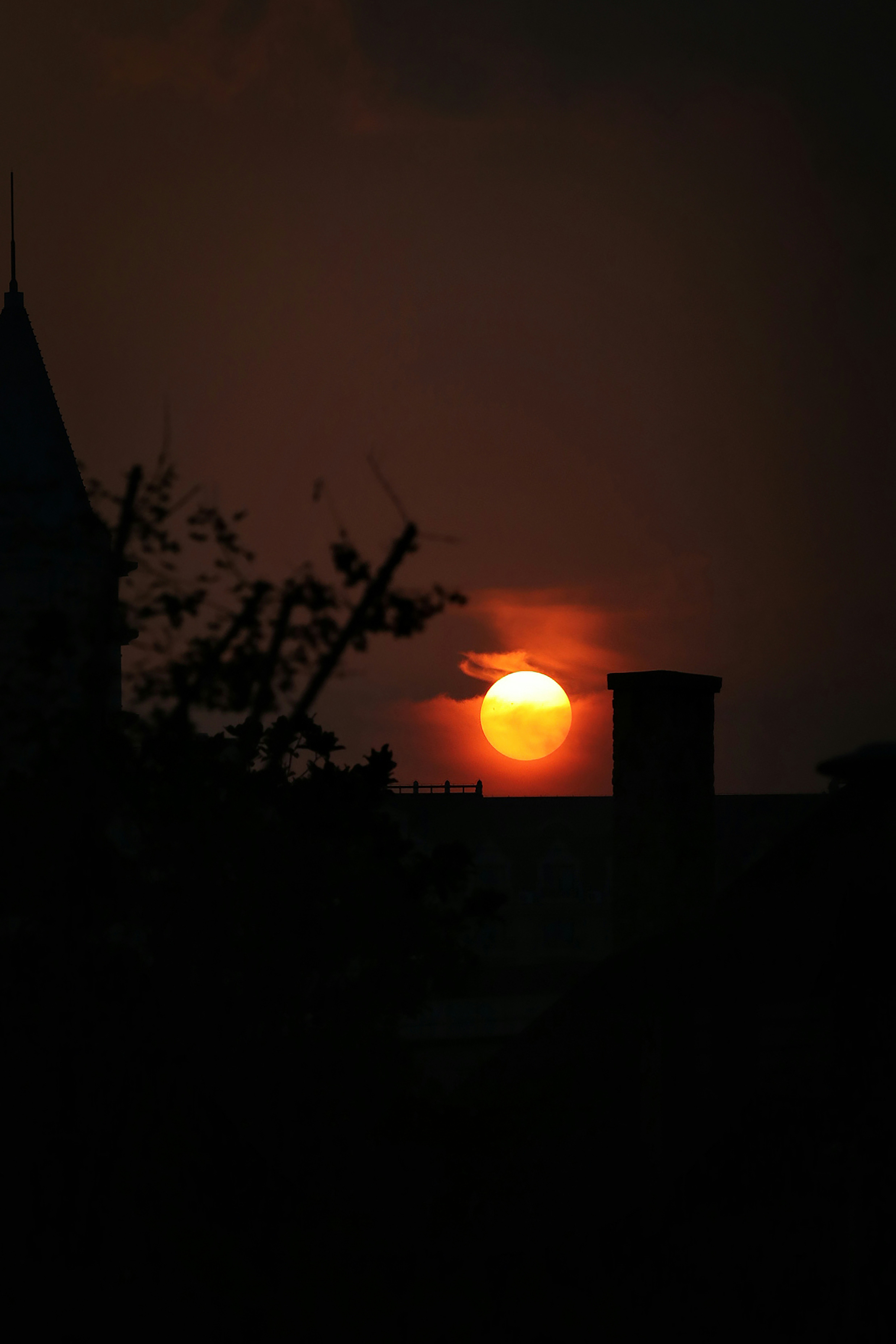 The sunset is setting over a silhouette of roofs.