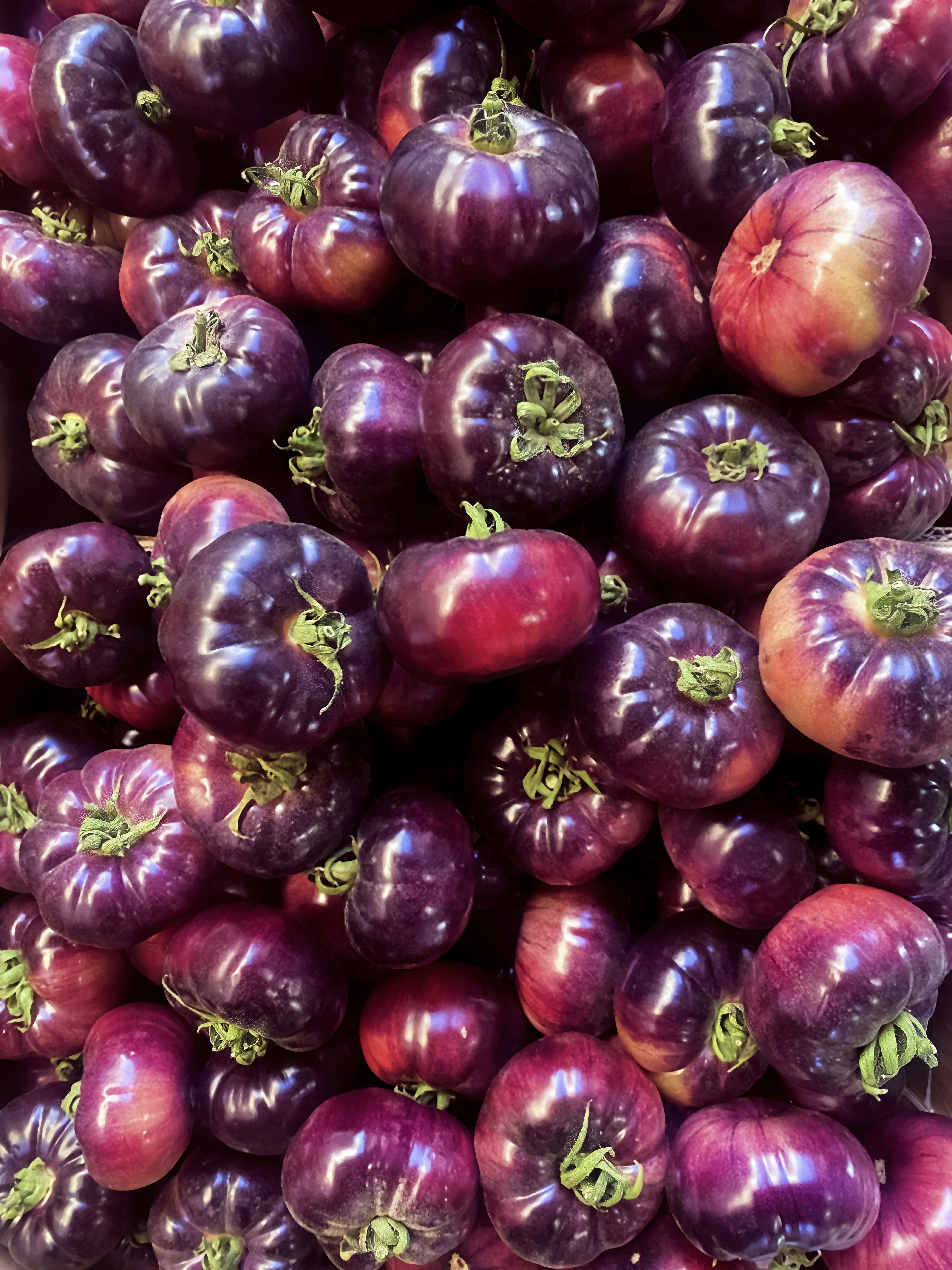 A pile of colorful, purple tomatoes.