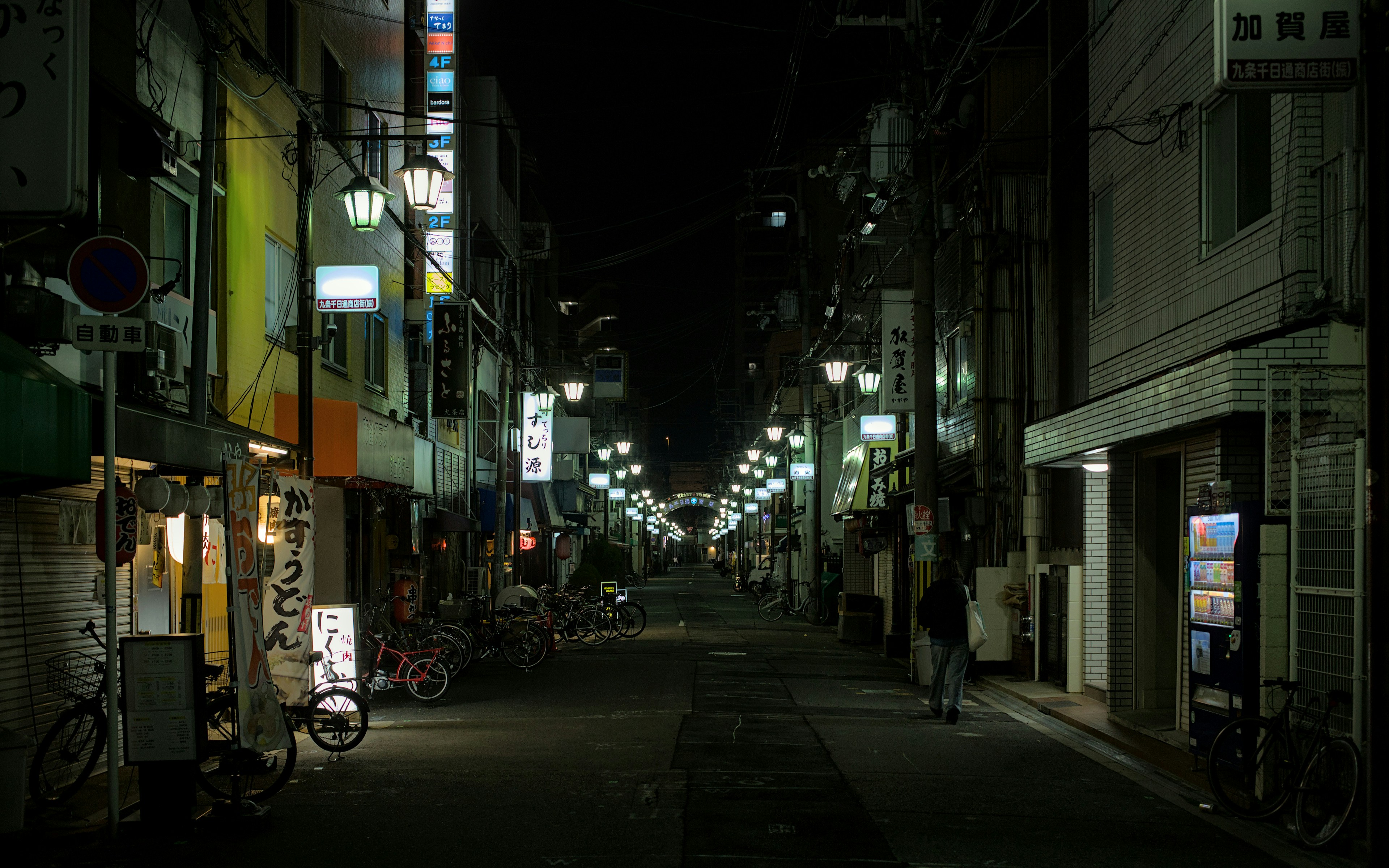 Brightly lit Japanese street at night with open shops