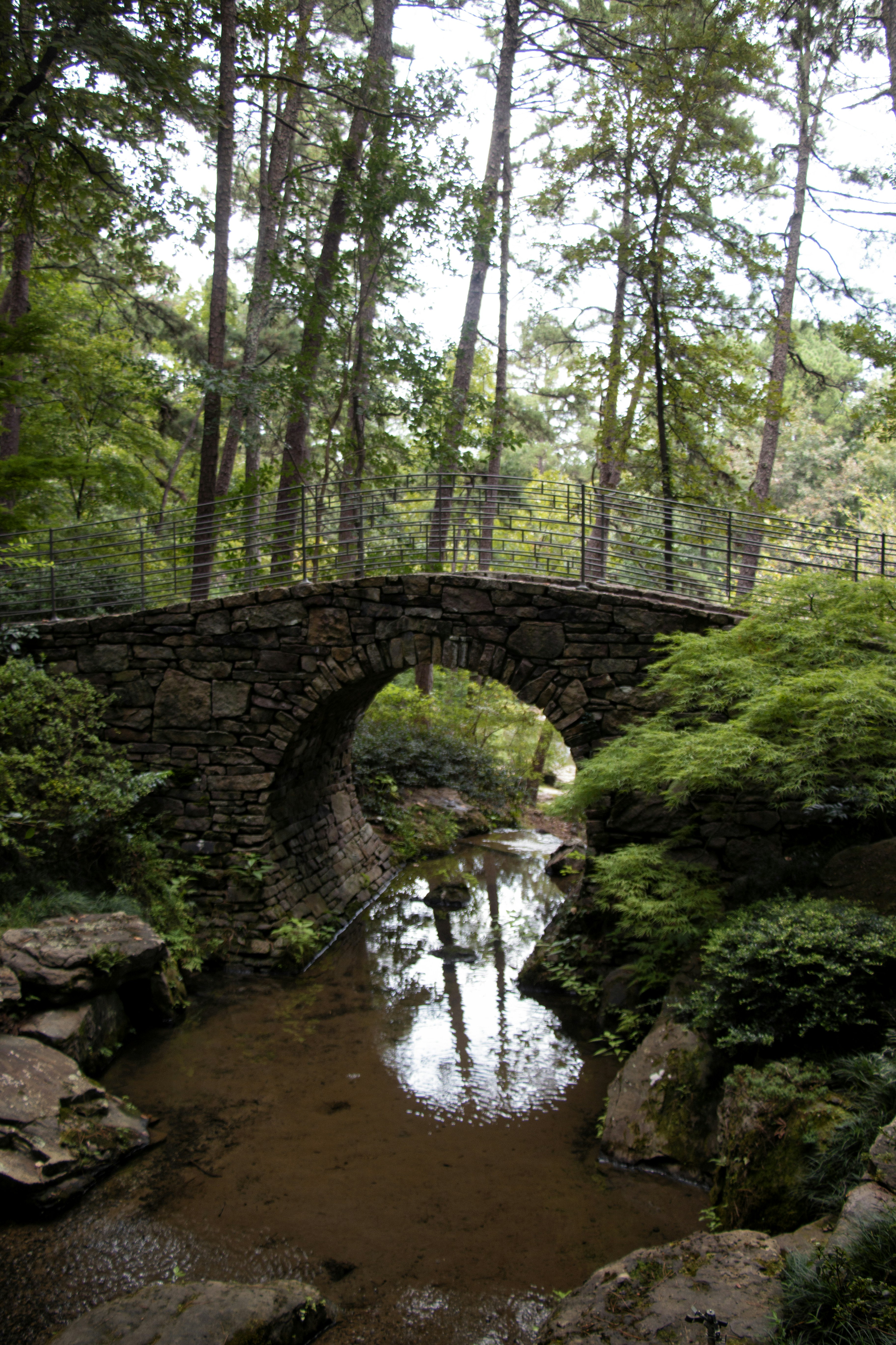 A stone bridge arches over a clear stream.