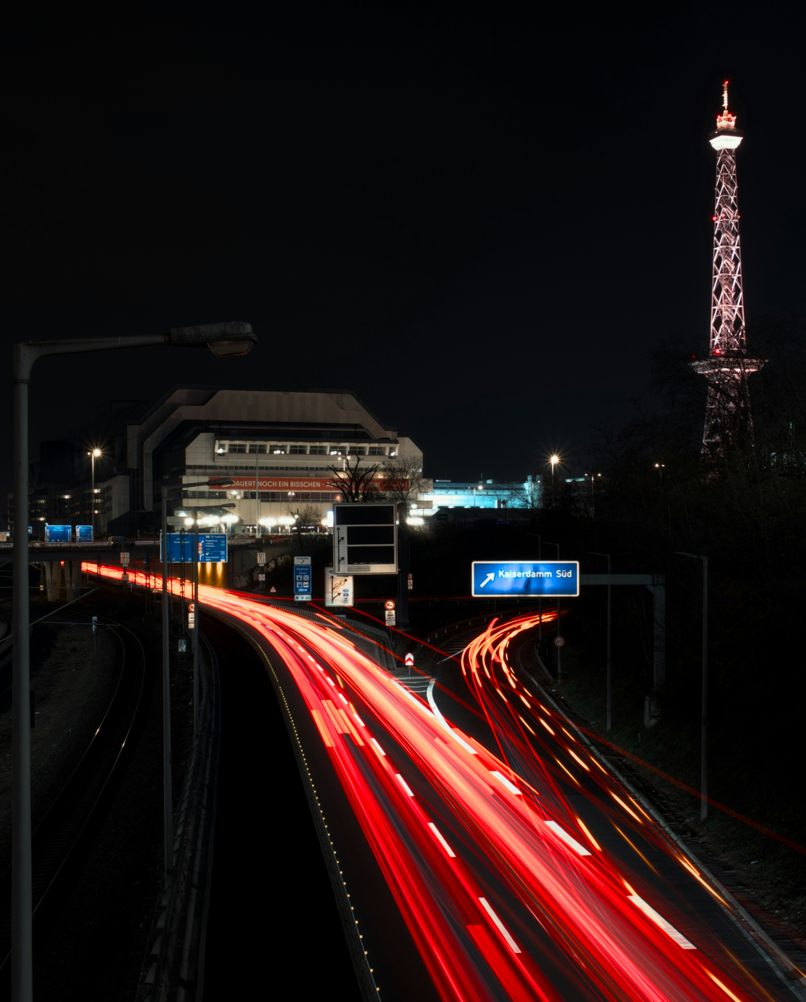 Der nächtliche Autobahnverkehr fließt an einem Turm vorbei.