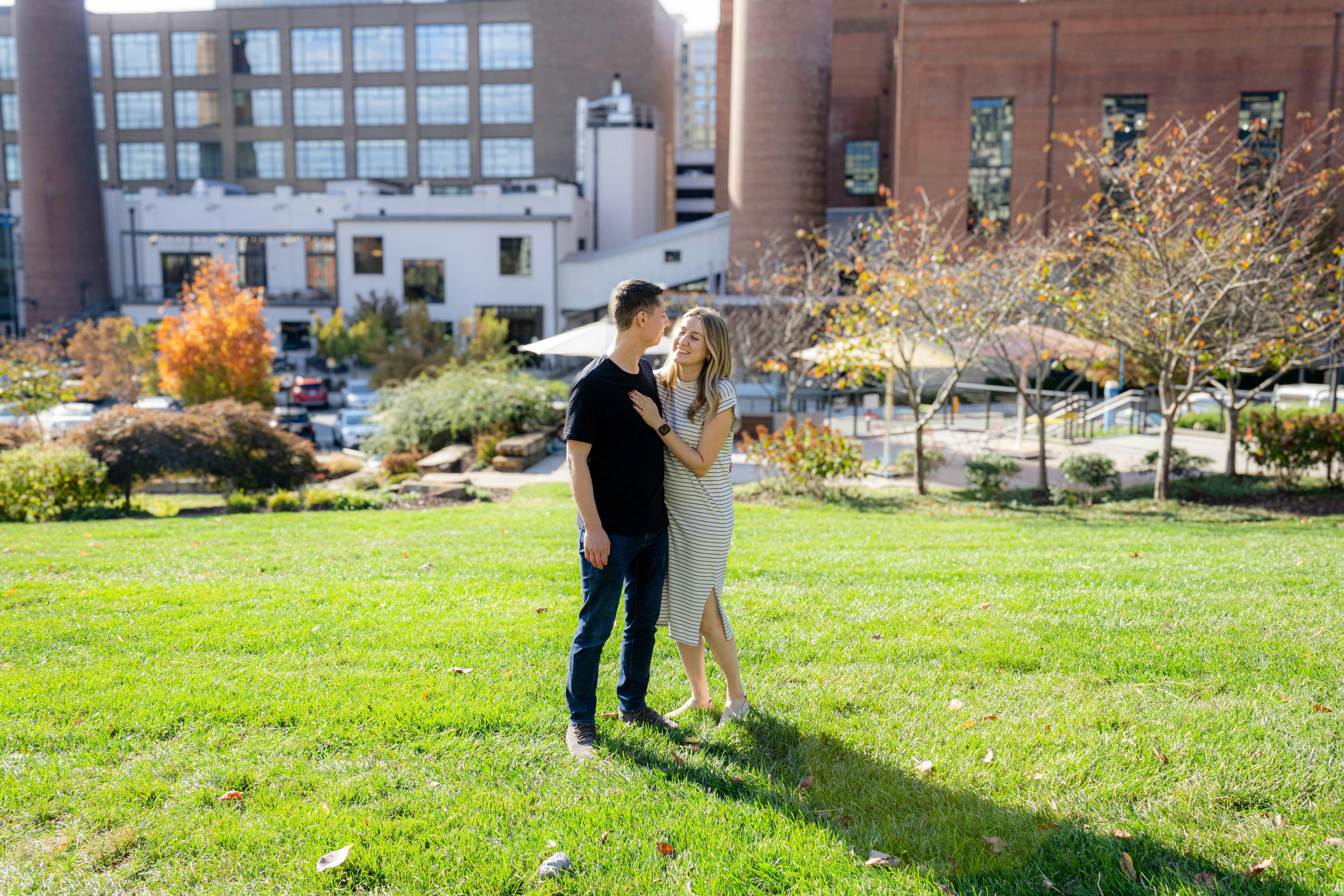 A couple smiles and poses in a park.
