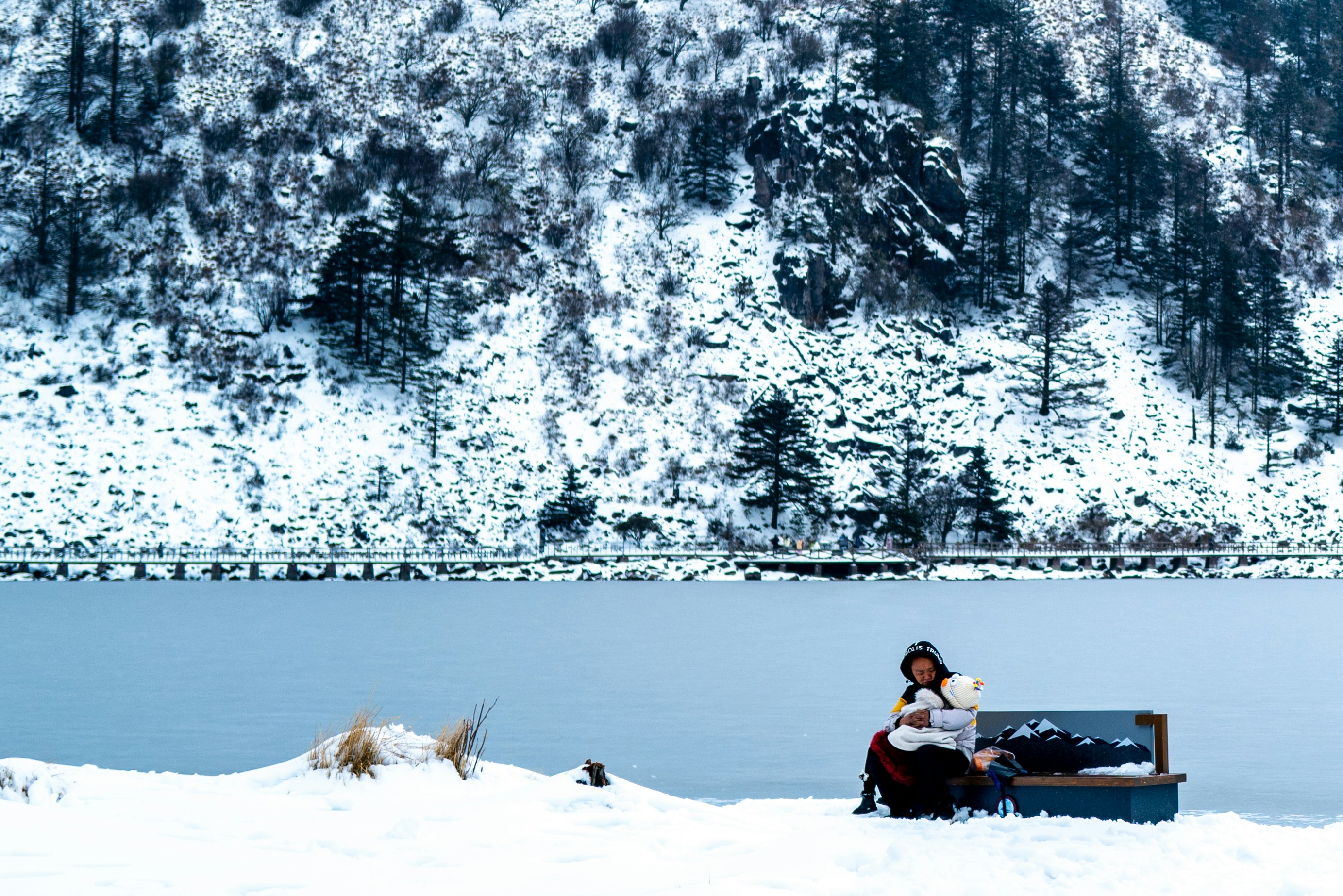Snowy landscape with person sitting on a bench.