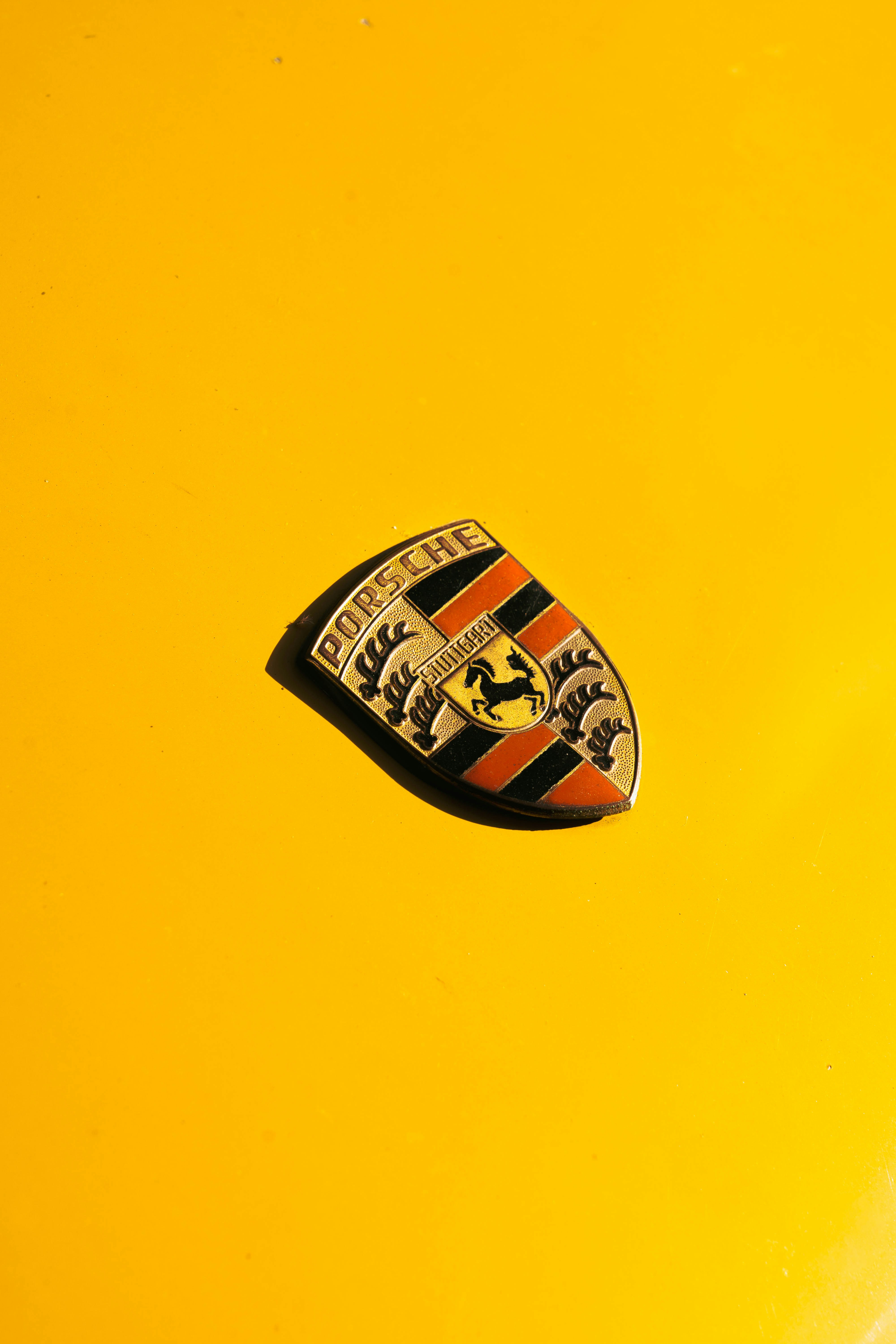 A porsche emblem on a bright yellow car.