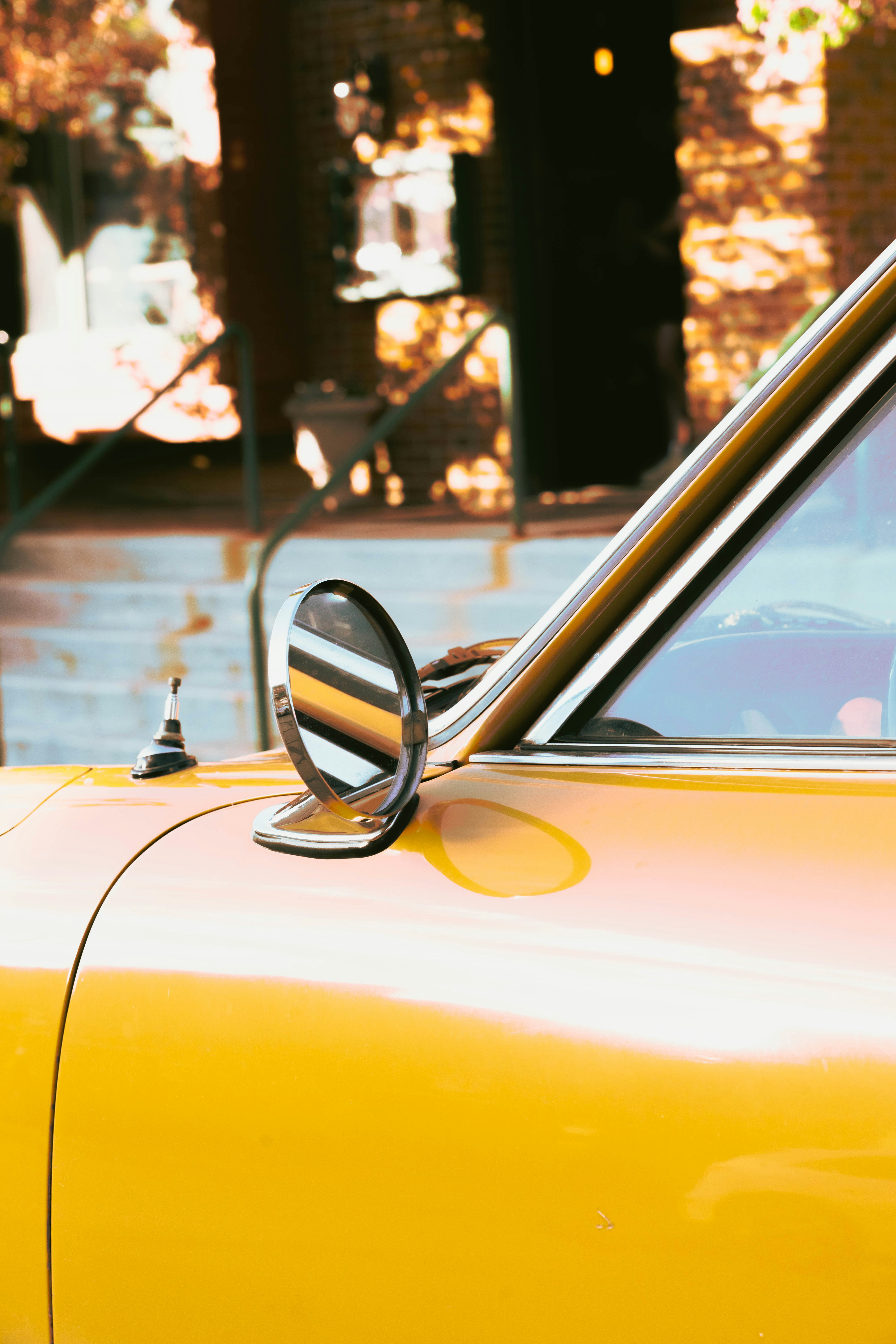 A yellow vintage car's side mirror is shown.