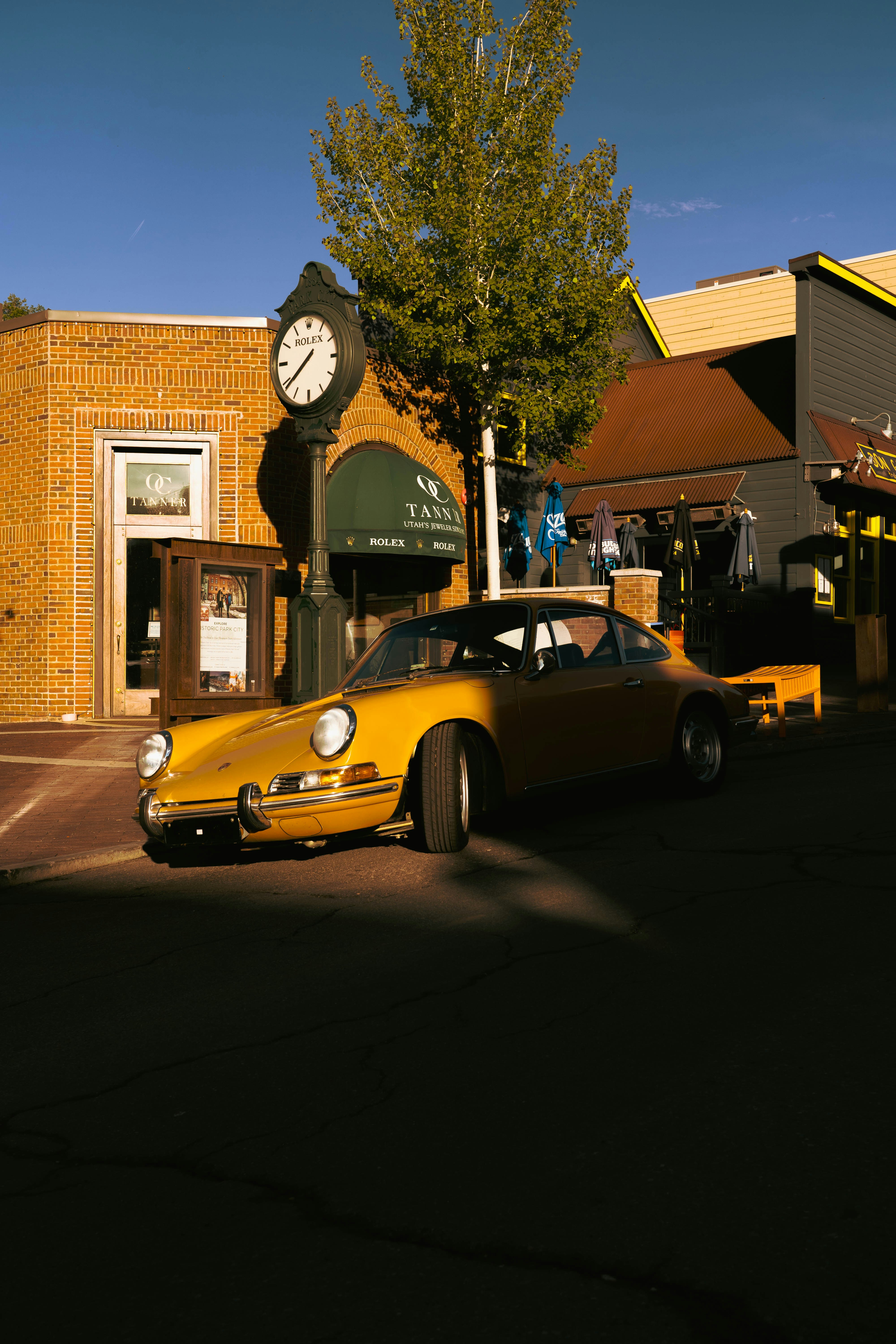 A yellow porsche parks in a quaint town.