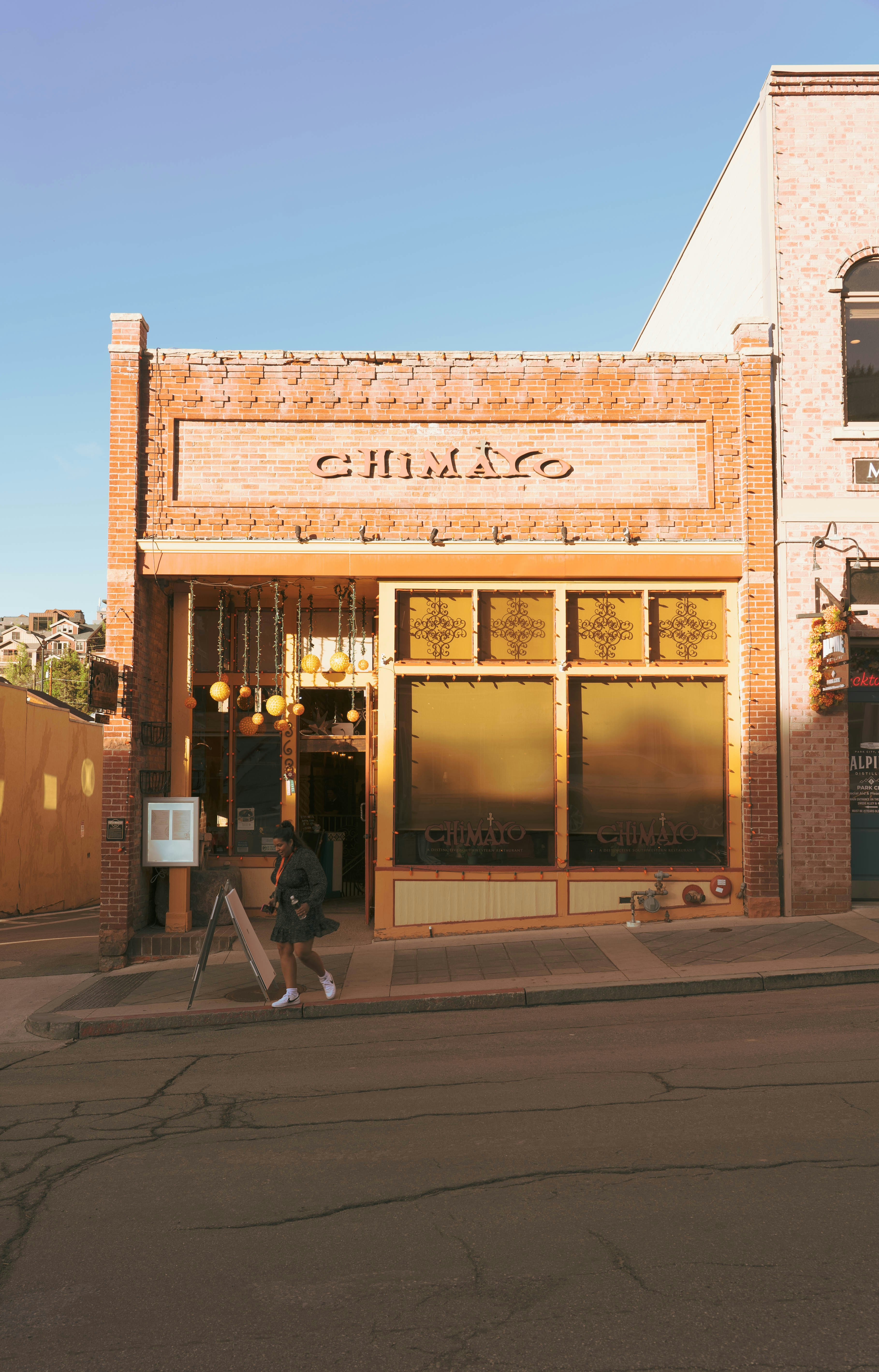 A person walks by a restaurant called chimayo.