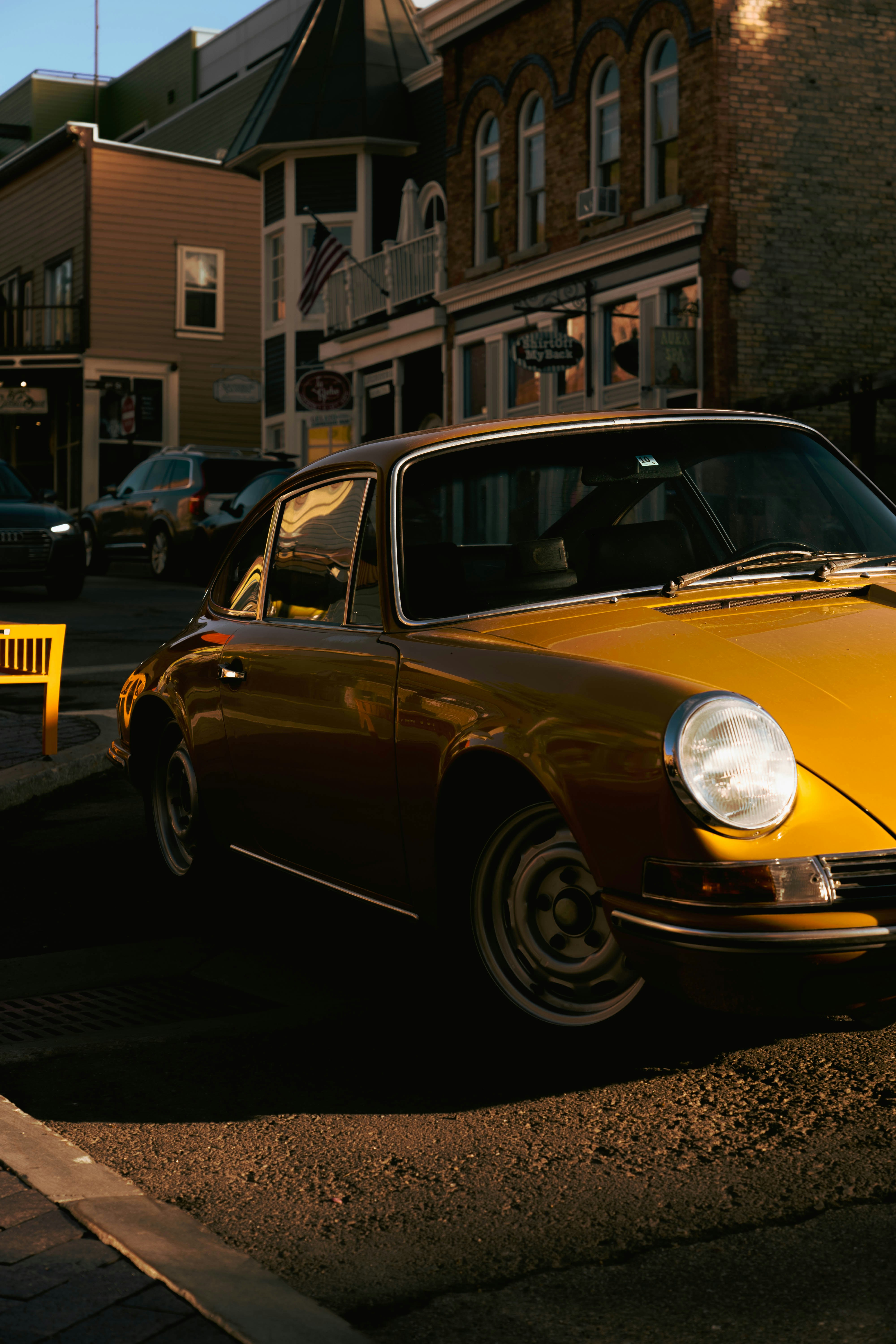 A classic yellow car is parked on a city street.