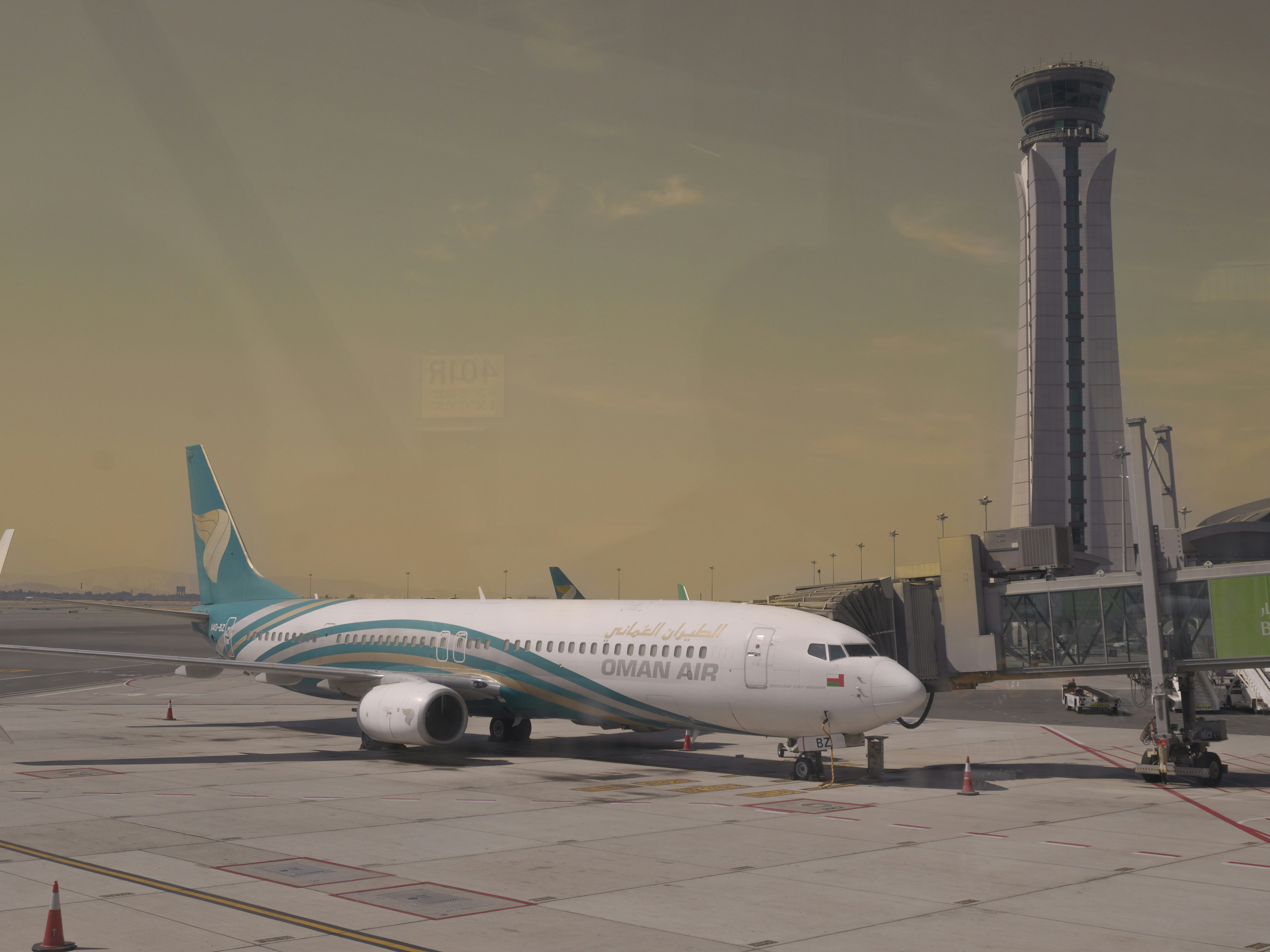 A plane is parked at the airport with the control tower.