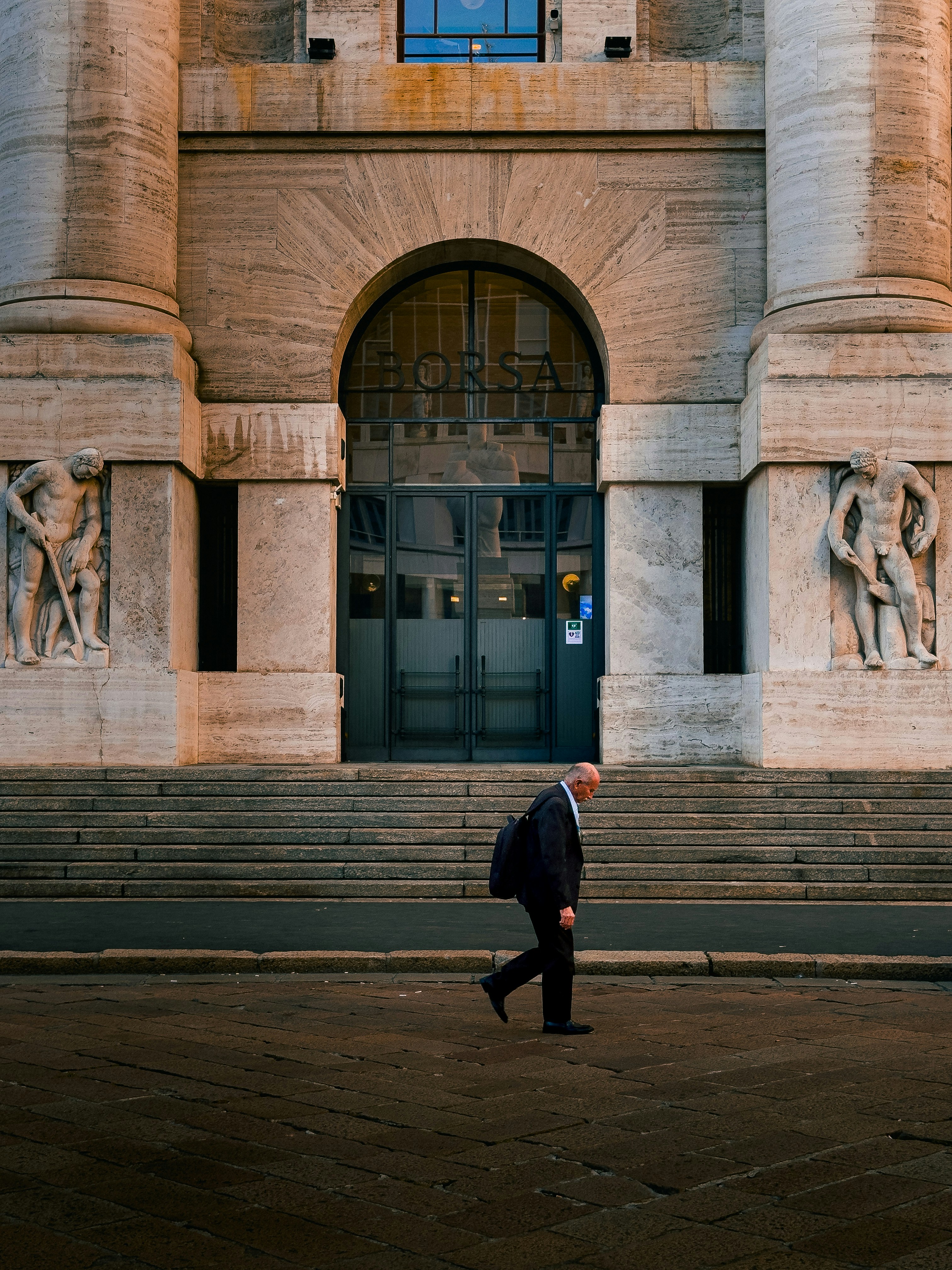 A man walks past a grand building.
