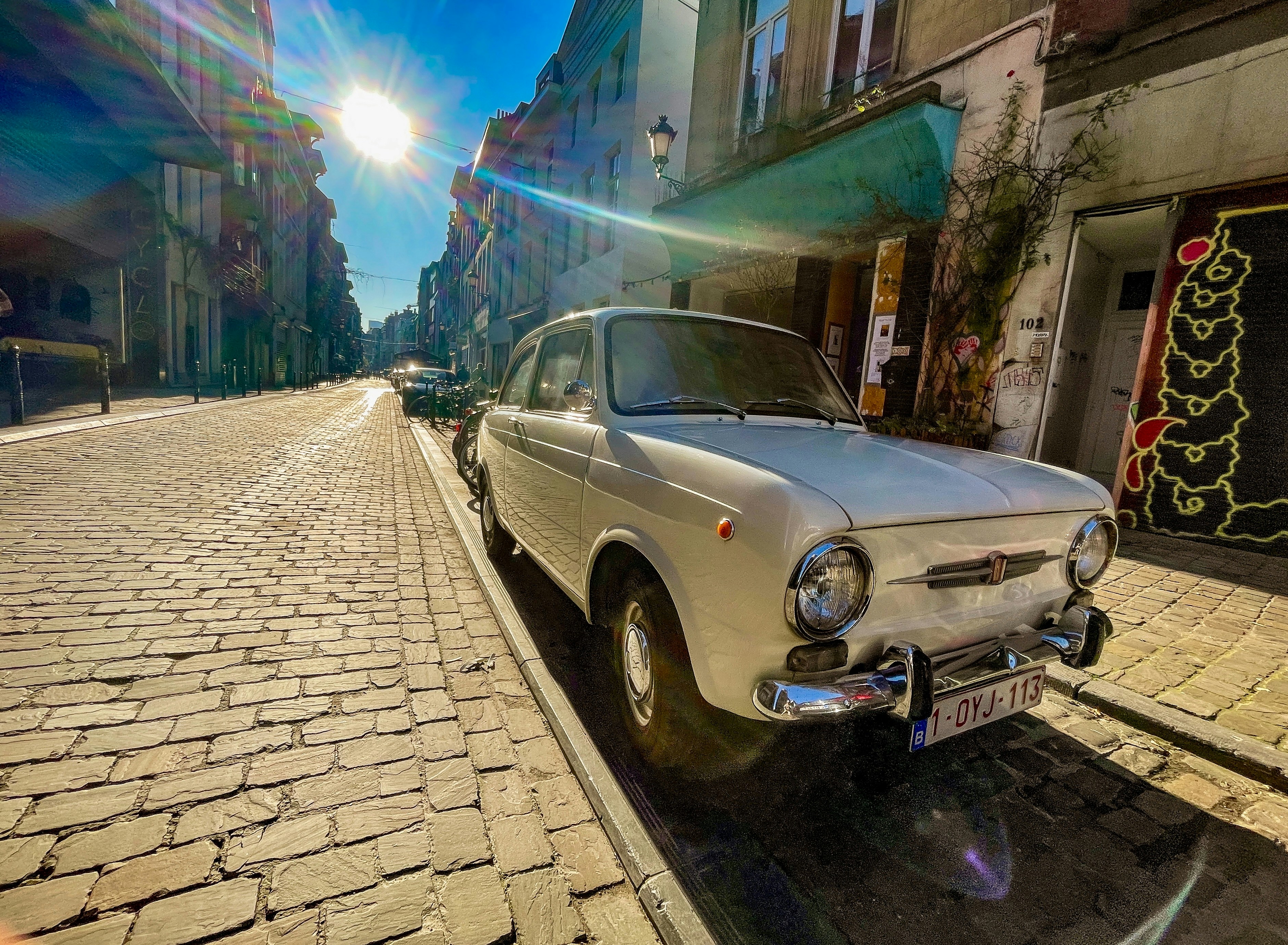 Coche de época aparcado en una soleada calle empedrada.
