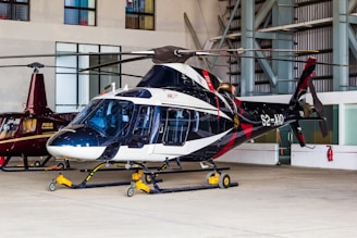 A sleek helicopter stands inside a hangar.