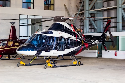 A sleek helicopter stands inside a hangar.