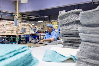 A worker handles fabric in a factory setting.