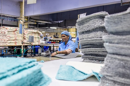 A worker handles fabric in a factory setting.